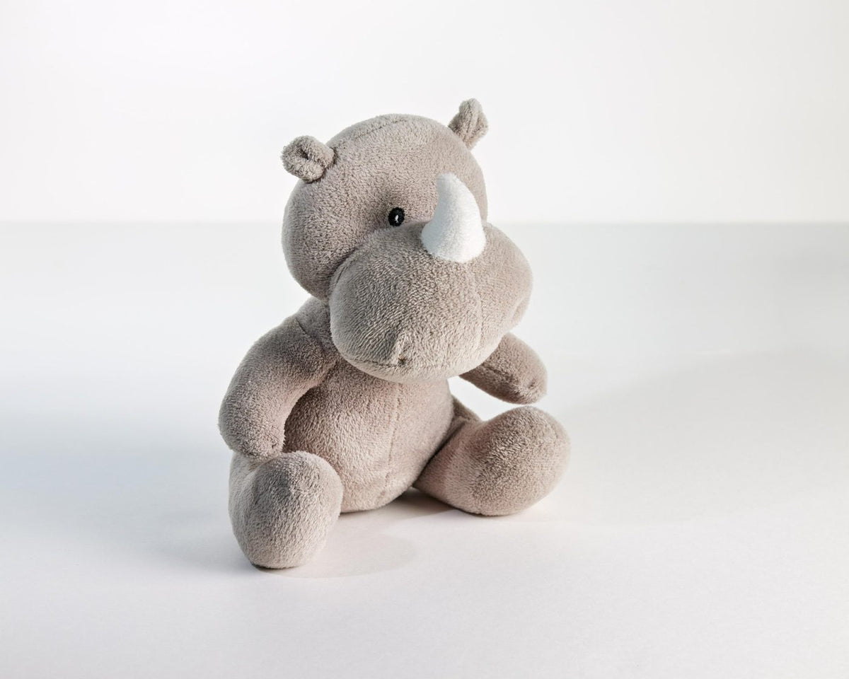 Soft grey rhino plush toy sitting on a white surface